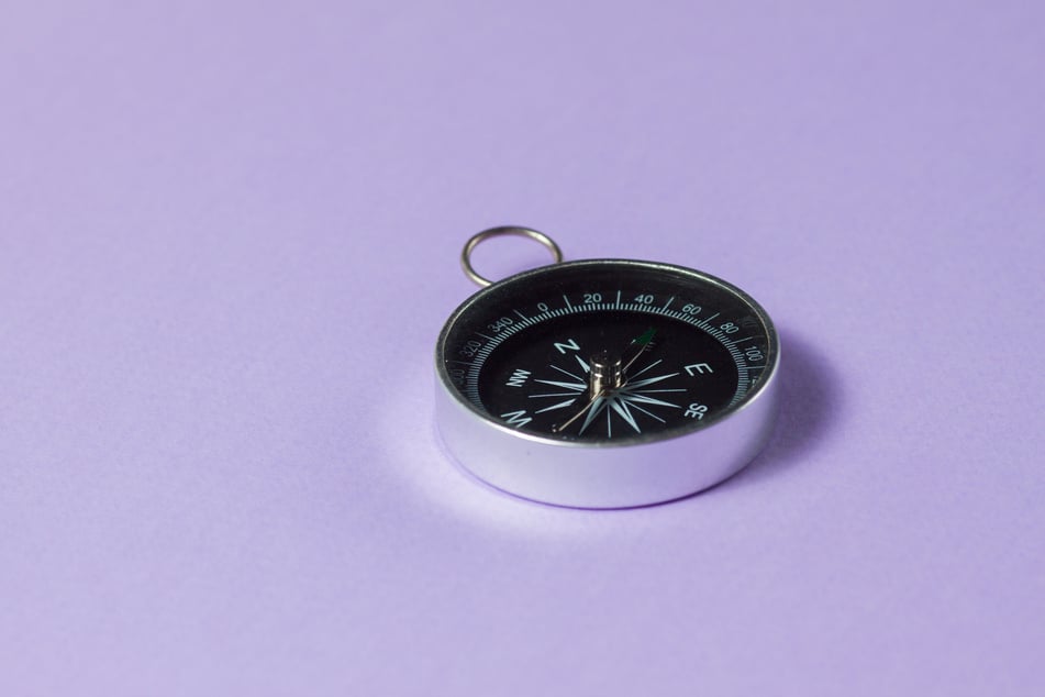 Compass on purple background. Concept signs symbols.